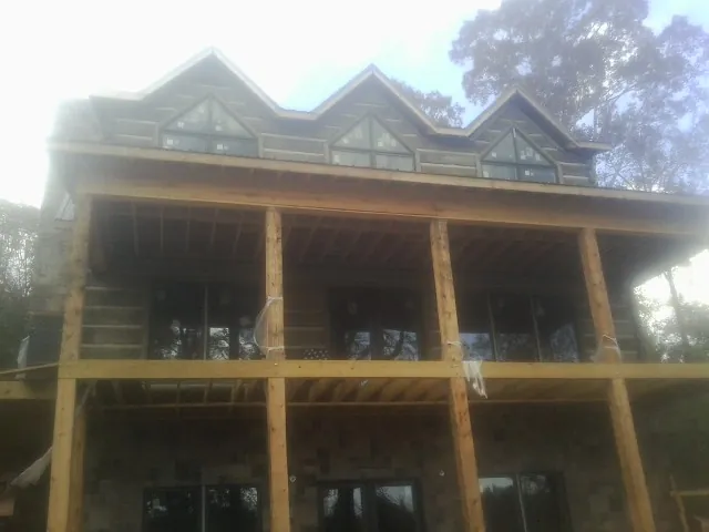 Dormers and porch framing on a large log home under construction — Roof Coating work by our crew in Armbrust