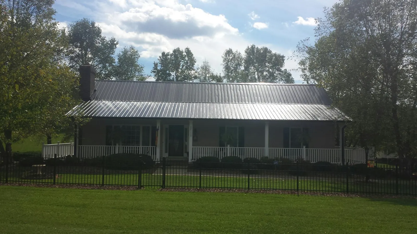 Gray metal roof on a brick ranch with a full width front porch — Gutter Guard Installation work by our crew in Armbrust