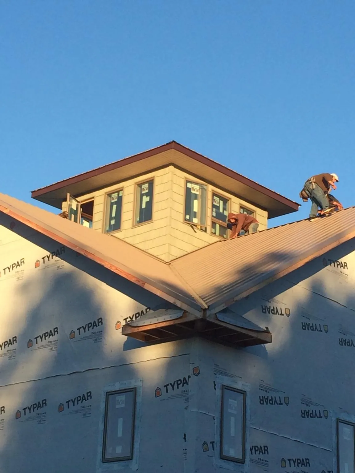 Roofers working around a rooftop cupola on a new metal roof at sunset — Roof Waterproofing in Armbrust by Roofing Brothers